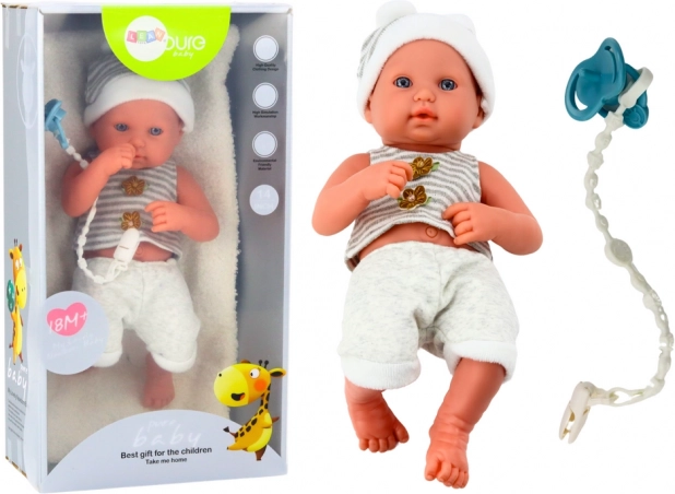 Realistische Babypuppe im weiß‑grauen Outfit mit Schnullerband und Decke