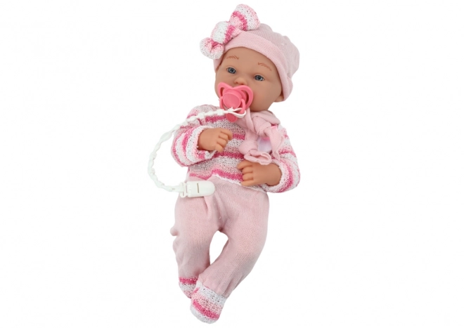 Babypuppe mit gestreiftem Pullover, Mütze und Schal in Rosa