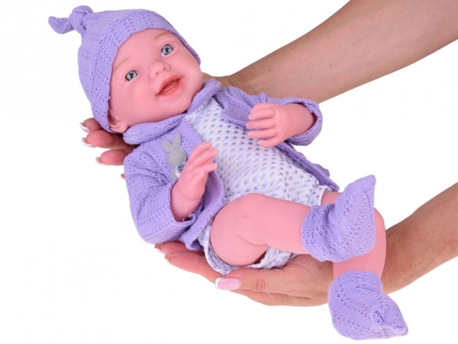 Lächelnde Babypuppe mit violettem Pullover