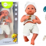 Realistische Babypuppe im weiß‑grauen Outfit mit Schnullerband und Decke
